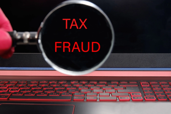 computer monitor with red text tax fraud through magnifying glass